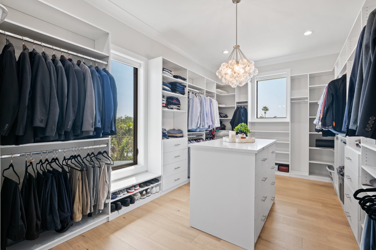 Walk-in closet with white built-in cabinetry, a central island and a cluster-globe chandelier
