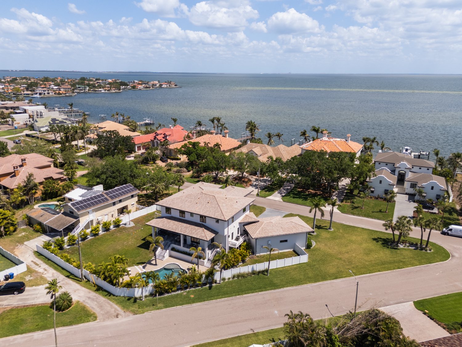 Aerial view of a waterfront new build in St. Petersburg, pool and screened lanai in the foreground and open Tampa Bay water behind